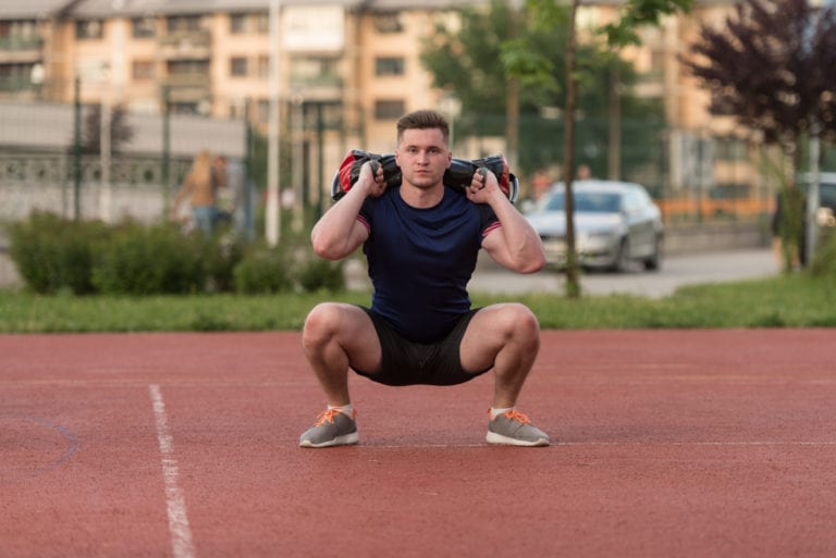 Young Man Doing Bag Squat Exercise Outdoor On Target Publications